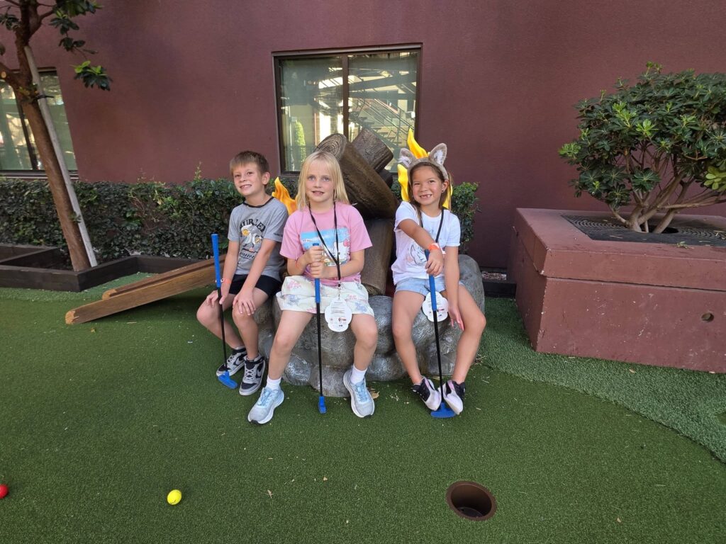 Kids putting a golf ball during a Great Wolf Lodge mini golf adventure. Included with the Wolf Pass.